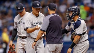 ST. PETERSBURG, FL - SEPTEMBER 26: Masahiro Tanaka #19 of the New York Yankees passes the ball off to manager Aaron Boone #17 as Luke Voit #45, left, and Gary Sanchez #24 join them on the mound in the fifth inning of a baseball game against the Tampa Bay Rays at Tropicana Field on September 26, 2018 in St. Petersburg, Florida. (Photo by Mike Carlson/Getty Images)