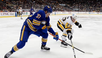 Dec 10, 2022; Pittsburgh, Pennsylvania, USA; Buffalo Sabres center Casey Mittelstadt (37) and Pittsburgh Penguins left wing Brock McGinn (23) reach for the puck during the second period at PPG Paints Arena. Mandatory Credit: Charles LeClaire-USA TODAY Sports