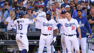 LOS ANGELES, CA - OCTOBER 17: Justin Turner #10 of the Los Angeles Dodgers is greeted by teammates Yasiel Puig #66 and Joc Pederson #31 at the entrance to the dugout after Turner scored during the sixth inning of Game Five of the National League Championship Series against the Milwaukee Brewers at Dodger Stadium on October 17, 2018 in Los Angeles, California. (Photo by Harry How/Getty Images)