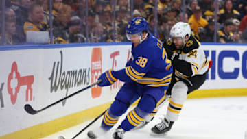 Mar 19, 2023; Buffalo, New York, USA; Buffalo Sabres defenseman Kale Clague (38) tries to clear the puck as Boston Bruins left wing Jake DeBrusk (74) defends during the first period at KeyBank Center. Mandatory Credit: Timothy T. Ludwig-USA TODAY Sports