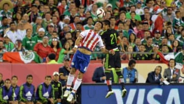 Mar 31, 2015; Kansas City, MO, USA; Paraguay forward Lucas Barrios (8) and Mexico defender Julio Cesar Dominguez (21) head the ball during the first half of the match at Arrowhead Stadium. Mandatory Credit: Denny Medley-USA TODAY Sports