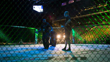Workers hold cans of adhesive grip spray inside the octagon before the start of Ultimate Fighting Championship (UFC) Fight Night at Cotai Arena, inside the Venetian Macao resort and casino, operated by Sands China Ltd., a unit of Las Vegas Sands Corp., in Macau, China, on Saturday, Aug. 23, 2014. UFC, the largest pay-per-view event provider, broadcasts to more than 800 million homes worldwide. Photographer: Brent Lewin/Bloomberg via Getty Images