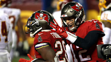 LANDOVER, MARYLAND - JANUARY 09: Quarterback Tom Brady #12 of the Tampa Bay Buccaneers congratulates running back Leonard Fournette #28 after a touchdown during the 4th quarter of the game against the Washington Football Team at FedExField on January 09, 2021 in Landover, Maryland. (Photo by Patrick Smith/Getty Images)