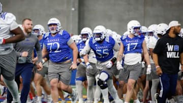 Kansas players run to their respected areas after a breakdown during Tuesday's practice inside the Kansas Indoor Practice Facility.