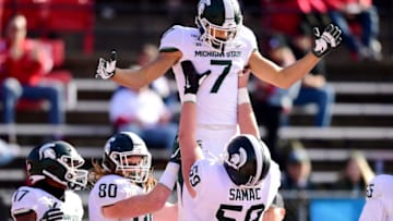 PISCATAWAY, NEW JERSEY - NOVEMBER 23: Nick Samac #59 of the Michigan State Spartans lifts up Cody White #7 after his touchdown in the first half of their game against the Rutgers Scarlet Knights at SHI Stadium on November 23, 2019 in Piscataway, New Jersey. (Photo by Emilee Chinn/Getty Images)
