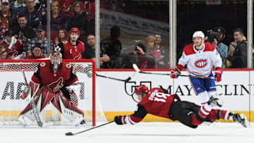 GLENDALE, ARIZONA - OCTOBER 30: Christian Dvorak #18 of the Arizona Coyotes dives for a loose puck as teammates Antti Raanta #32 and Oliver Ekman-Larsson #23 look on while Joel Armia #40 of the Montreal Canadiens skates to the puck at Gila River Arena on October 30, 2019 in Glendale, Arizona. (Photo by Norm Hall/NHLI via Getty Images)