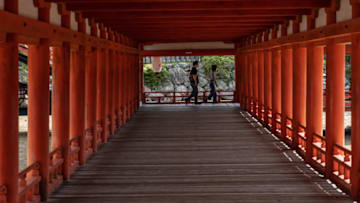 ITSUKUSHIMA, JAPAN - MAY 18: A couple wearing face masks pass along a walkway in Itsukushima Shrine on May 18, 2021 in Itsukushima, Japan. Hiroshima, where Itsukushima island is located, is one of the latest prefectures to be placed under a state of emergency as the country grapples with a fourth wave of Covid-19 with less than three months to go to the Tokyo Olympics. (Photo by Carl Court/Getty Images)