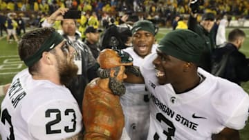 ANN ARBOR, MI - OCTOBER 07: Chris Frey #23 and LJ Scott #3 of the Michigan State Spartans celebrate the win over Michigan Wolverines with the Paul Banyun trophy at Michigan Stadium on October 7, 2017 in Ann Arbor, Michigan. Michigan State defeated Michigan 14-10. (Photo by Leon Halip/Getty Images)