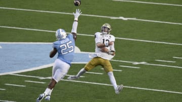 Notre Dame Fighting Irish quarterback Ian Book (12) passes the ball as North Carolina Tar Heels linebacker Kaimon Rucker (25) pressures in the second quarter at Kenan Memorial Stadium. Mandatory Credit: Bob Donnan-USA TODAY Sports