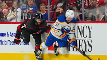 Nov 4, 2022; Raleigh, North Carolina, USA; Buffalo Sabres center Casey Mittelstadt (37) is checked by Carolina Hurricanes defenseman Jalen Chatfield (5) during the first period at PNC Arena. Mandatory Credit: James Guillory-USA TODAY Sports