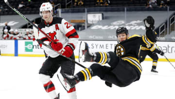 BOSTON, MASSACHUSETTS - MARCH 30: Jeremy Lauzon #55 of the Boston Bruins falls over Damon Severson #28 of the New Jersey Devils during the first period at TD Garden on March 30, 2021 in Boston, Massachusetts. (Photo by Maddie Meyer/Getty Images)