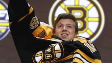 Jun 24, 2016; Buffalo, NY, USA; Charles McAvoy puts on a team jersey after being selected as the number fourteen overall draft pick by the Boston Bruins in the first round of the 2016 NHL Draft at the First Niagra Center. Mandatory Credit: Timothy T. Ludwig-USA TODAY Sports