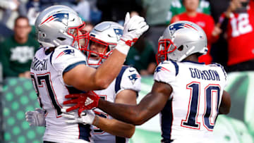 EAST RUTHERFORD, NEW JERSEY - NOVEMBER 25: Rob Gronkowski #87 of the New England Patriots is congratulated by his teammates Chris Hogan #15 and Josh Gordon #10 after his first quarter touchdown reception against the New York Jets at MetLife Stadium on November 25, 2018 in East Rutherford, New Jersey. (Photo by Jeff Zelevansky/Getty Images)
