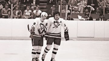 PITTSBURGH, PA - CIRCA 1976: (EDITORS NOTE: Image has been shot in black and white. Color version not available.) Winger Lowell MacDonald #18 and center Syl Apps, Jr. #26 of the Pittsburgh Penguins look on from the ice during a timeout during a National Hockey League game at the Civic Arena circa 1976 in Pittsburgh, Pennsylvania. (Photo by George Gojkovich/Getty Images)