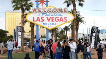 LAS VEGAS, NV - MARCH 27: Visitors line up to take photos in front of the Welcome to Fabulous Las Vegas sign after Oakland Raiders fans placed team banners in the background after National Football League owners voted 31-1 to approve the team's application to relocate to Las Vegas during their annual meeting on March 27, 2017 in Las Vegas, Nevada. The Raiders are expected to begin play no later than 2020 in a planned 65,000-seat domed stadium to be built in Las Vegas at a cost of about USD 1.9 billion. (Photo by Ethan Miller/Getty Images)