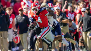 Nov 20, 2021; Athens, Georgia, USA; Georgia Bulldogs running back James Cook (4) runs with Charleston Southern Buccaneers defensive back Matthew Williams (1) on his back during the first half at Sanford Stadium. Mandatory Credit: Dale Zanine-USA TODAY Sports