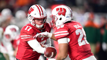 NEW YORK, NEW YORK - DECEMBER 27: Jack Coan #17 of the Wisconsin Badgers hands the ball off to teammate Taiwan Deal #28 in the first quarter of the New Era Pinstripe Bowl against the Miami Hurricanes at Yankee Stadium on December 27, 2018 in the Bronx borough of New York City. (Photo by Sarah Stier/Getty Images)