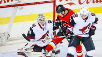 Jan 7, 2016; Calgary, Alberta, CAN; Arizona Coyotes goalie Louis Domingue (35) makes a save as Calgary Flames left wing Micheal Ferland (79) and Arizona Coyotes defenseman Michael Stone (26) battle for the puck during the first period at Scotiabank Saddledome. Mandatory Credit: Sergei Belski-USA TODAY Sports