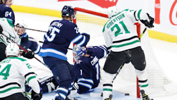 Nov 2, 2021; Winnipeg, Manitoba, CAN; Dallas Stars left wing Jason Robertson (21) scores on Winnipeg Jets goaltender Eric Comrie (1) in the third period at Canada Life Centre. Mandatory Credit: James Carey Lauder-USA TODAY Sports