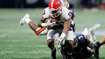 ATLANTA, GA - DECEMBER 02: Elijah Holyfield #13 of the Georgia football Bulldogs is tackled by Jamel Dean #12 of the Auburn Tigers on a run during the second half against the Auburn Tigers in the SEC Championship at Mercedes-Benz Stadium on December 2, 2017 in Atlanta, Georgia. (Photo by Jamie Squire/Getty Images)