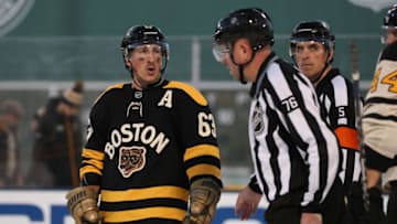 Jan 2, 2023; Boston, Massachusetts, USA; Boston Bruins left wing Brad Marchand (63) talks with linesman Michel Cormier (76) at the end of the second period of the 2023 Winter Classic ice hockey game against the Pittsburgh Penguins at Fenway Park. Mandatory Credit: Paul Rutherford-USA TODAY Sports