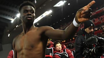 Arsenal's English midfielder Bukayo Saka comes over to give away his shirt to a fan after the English League Cup semi-final first leg football match between Liverpool and Arsenal at Anfield in Liverpool, north west England on January 13, 2022. - The game finished 0-0. - RESTRICTED TO EDITORIAL USE. No use with unauthorized audio, video, data, fixture lists, club/league logos or 'live' services. Online in-match use limited to 120 images. An additional 40 images may be used in extra time. No video emulation. Social media in-match use limited to 120 images. An additional 40 images may be used in extra time. No use in betting publications, games or single club/league/player publications. (Photo by Paul ELLIS / AFP) / RESTRICTED TO EDITORIAL USE. No use with unauthorized audio, video, data, fixture lists, club/league logos or 'live' services. Online in-match use limited to 120 images. An additional 40 images may be used in extra time. No video emulation. Social media in-match use limited to 120 images. An additional 40 images may be used in extra time. No use in betting publications, games or single club/league/player publications. / RESTRICTED TO EDITORIAL USE. No use with unauthorized audio, video, data, fixture lists, club/league logos or 'live' services. Online in-match use limited to 120 images. An additional 40 images may be used in extra time. No video emulation. Social media in-match use limited to 120 images. An additional 40 images may be used in extra time. No use in betting publications, games or single club/league/player publications. (Photo by PAUL ELLIS/AFP via Getty Images)