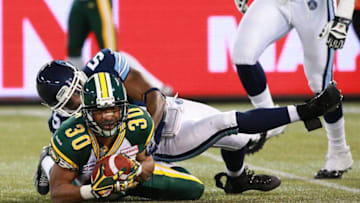 John White #30 of the Edmonton Eskimos recovers a fumble as he is tackled by Jermaine Gabriel #5 of the Toronto Argonauts during their game. (Photo by Dave Sandford/Getty Images)