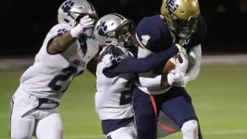 Macomb Dakota defenders De'javion Stepney, left, and Nico Vitale, center, tackle Grosse Pointe South receiver Will Johnson during the second half at Grosse Pointe South high school Friday, Oct. 2, 2020.Preps Dakota