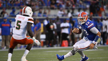 ORLANDO, FL - AUGUST 24: Feleipe Franks #13 of the Florida Gators tries to avoid the tackle of Amari Carter #5 of the Miami Hurricanes in the first half in the Camping World Kickoff at Camping World Stadium on August 24, 2019 in Orlando, Florida.(Photo by Mark Brown/Getty Images)