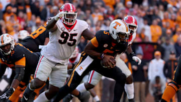 Hendon Hooker of the Tennessee Volunteers drops back to pass while being chased by Devonte Wyatt. (Photo by Dylan Buell/Getty Images)
