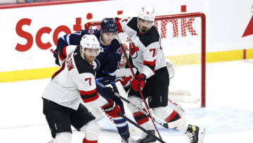 Winnipeg Jets left wing Adam Lowry (17) is sandwiched between New Jersey Devils defenseman Dougie Hamilton (7) and New Jersey Devils defenseman Jonas Siegenthaler (71) in the third period at Canada Life Centre. Mandatory Credit: James Carey Lauder-USA TODAY Sports