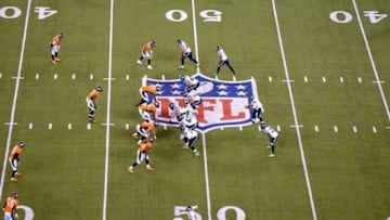 Feb 2, 2014; East Rutherford, NJ, USA; General view of the NFL logo at midifeld as Seattle Seahawks quarterback Russell Wilson takes the snap against the Denver Broncos in Super Bowl XLVIII at MetLife Stadium. The Seahawks defeated the Broncos 43-8. Mandatory Credit: Kirby Lee-USA TODAY Sports