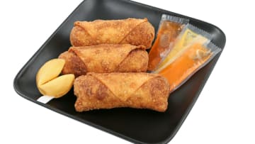A plate of Chinese takeout with egg rolls and duck sauce