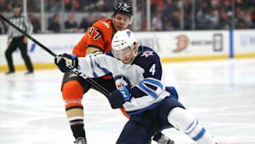 ANAHEIM, CALIFORNIA - NOVEMBER 29: Neal Pionk #4 of the Winnipeg Jets is pushed down by Hampus Lindholm #47 of the Anaheim Ducks during the second period of a game at Honda Center on November 29, 2019 in Anaheim, California. (Photo by Sean M. Haffey/Getty Images)