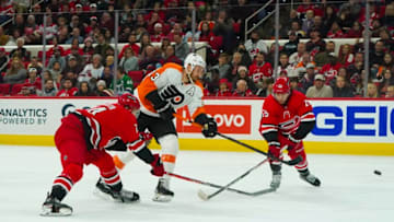 Mar 12, 2022; Raleigh, North Carolina, USA; Philadelphia Flyers center Kevin Hayes (13) gets the shot away against Carolina Hurricanes defenseman Jaccob Slavin (74) and defenseman Ethan Bear (25) during the second period at PNC Arena. Mandatory Credit: James Guillory-USA TODAY Sports