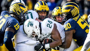Michigan State's Elijah Collins, center, is tackled by Michigan's Michael Dwumfour, right, during the second quarter on Saturday, Nov. 16, 2019, at Michigan Stadium in Ann Arbor.191116 Msu Um 212a