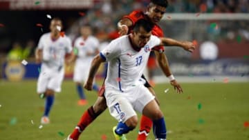 Sep 6, 2014; Santa Clara, CA, USA; Chile defender Gary Medel (17) controls the ball ahead of Mexico defender Miguel Ponce Briseno (16) as confetti falls onto the field during the second half at Levi