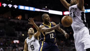 Nov 26, 2014; San Antonio, TX, USA; Indiana Pacers point guard A.J. Price (12) passes the ball around San Antonio Spurs power forward Tim Duncan (21) during the first half at AT&T Center. Mandatory Credit: Soobum Im-USA TODAY Sports