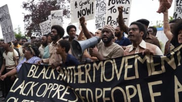 Small Axe. Pictured: Letitia Wright as Altheia Jones-LeCointe (center, dark blue shirt) and Malachi Kirby as Darcus Howe (center, holding megaphone) in "Mangrove." Photo Credit: Des Willie / Amazon Prime Video.Air Date: November 20, 2020