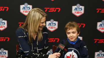 WINNIPEG, MB - MARCH 20: TSN reporter Sara Orlesky interviews Connolly Gamble, a Make-A-Wish recipient, during first intermission between the Winnipeg Jets and the Anaheim Ducks at the MTS Centre on March 20, 2016 in Winnipeg, Manitoba, Canada. Connolly's wish was to become a Winnipeg Jet for a game. (Photo by Jonathan Kozub/NHLI via Getty Images)