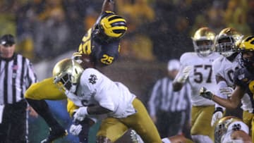 ANN ARBOR, MICHIGAN - OCTOBER 26: Hassan Haskins #25 of the Michigan Wolverines tries to jump over the tackle of Jeremiah Owusu-Koramoah #6 of the Notre Dame Fighting Irish during a first half run at Michigan Stadium on October 26, 2019 in Ann Arbor, Michigan. (Photo by Gregory Shamus/Getty Images)