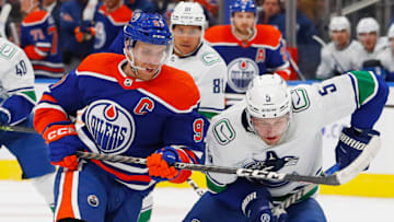 Edmonton Oilers forward Connor McDavid (97) battles for a loose puck with Vancouver Canucks defensemen Tucker Poolman (5) Mandatory Credit: Perry Nelson-USA TODAY Sports