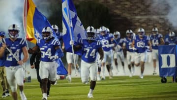 Nov 18, 2021; Durham, North Carolina, USA; Duke Blue Devils defensive tackle Michael Larbie (74) runs with a Duke flag during the 1st half of the game against the Louisville Cardinals at Wallace Wade Stadium. Mandatory Credit: Jaylynn Nash-USA TODAY Sports