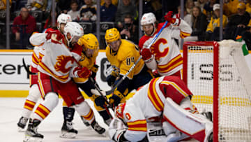 NASHVILLE, TN - APRIL 19: Dan Vladar #80 of the Calgary Flames stops the puck against the Nashville Predators as players from both teams battle during the first period at Bridgestone Arena on April 19, 2022 in Nashville, Tennessee. (Photo by Brett Carlsen/Getty Images)