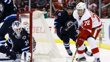 Mar 10, 2016; Detroit, MI, USA; Detroit Red Wings center Andreas Athanasiou (72) skates with the puck around the net of Winnipeg Jets goalie Michael Hutchinson (34) chased by defenseman Ben Chiarot (7) in the third period at Joe Louis Arena. Detroit won 3-2. Mandatory Credit: Rick Osentoski-USA TODAY Sports