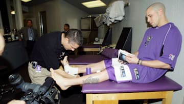 SACRAMENTO, CA - MARCH 15: Mike Bibby #10 of the Sacramento Kings reads a book while trainer Pete Youngman tapes him before the game against the Orlando Magic on March 15, 2005 at Arco Arena in Sacramento, California. NOTE TO USER: User expressly acknowledges and agrees that, by downloading and/or using this Photograph, User is consenting to the terms and conditions of the Getty Images License Agreement. Mandatory Copyright Notice: Copyright 2005 NBAE (Photo by Rocky Widner/NBAE via Getty Images)