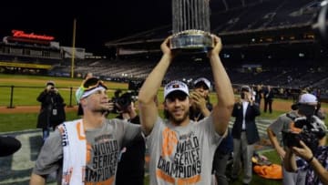 Oct 29, 2014; Kansas City, MO, USA; San Francisco Giants starting pitcher Ryan Vogelsong (left) watches as teammate Madison Bumgarner (middle) hoists the Commissioners Trophy after game seven of the 2014 World Series against the Kansas City Royals at Kauffman Stadium. Mandatory Credit: Peter G. Aiken-USA TODAY Sports