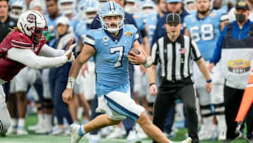 Dec 30, 2021; Charlotte, NC, USA; North Carolina Tar Heels quarterback Sam Howell (7) runs for yardage around end against the South Carolina Gamecocks during the second quarter at Bank of America Stadium. Mandatory Credit: Jim Dedmon-USA TODAY Sports