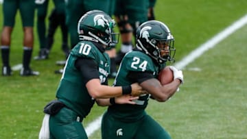 Michigan State quarterback Payton Thorne hands the ball to running back Elijah Collins during warmups before the Ohio State game at Spartan Stadium in East Lansing, Saturday, Dec. 5, 2020.