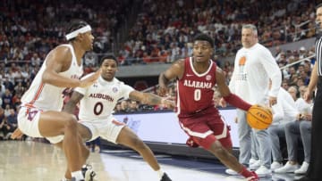 AUBURN, ALABAMA - FEBRUARY 11: Jaden Bradley #0 of the Alabama Crimson Tide looks to maneuver the ball by Dylan Cardwell #44 of the Auburn Tigers and K.D. Johnson #0 of the Auburn Tigers during the first half of play at Neville Arena on February 11, 2023 in Auburn, Alabama. (Photo by Michael Chang/Getty Images)
